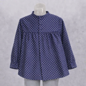 blusón infantil de manga larga 100 % algodón en color azul marino con estampado de pequeñas estrellas blancas. Presenta cuello redondo, cierre frontal con botones y un ligero fruncido en el pecho que aporta un diseño cómodo y elegante